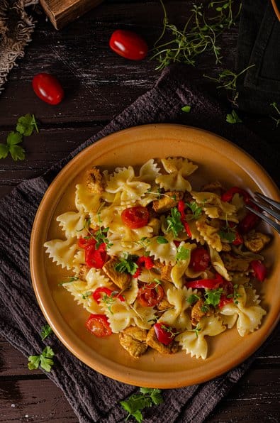 A vibrant plate of farfalle pasta tossed with fresh vegetables and herbs.