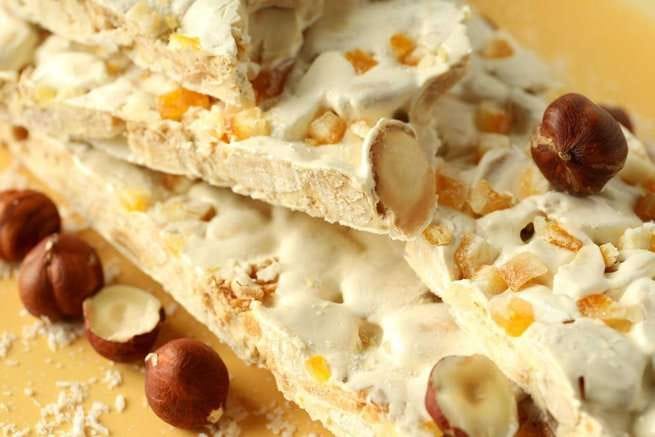 A slice of traditional turrón with almonds and a smooth, golden finish.