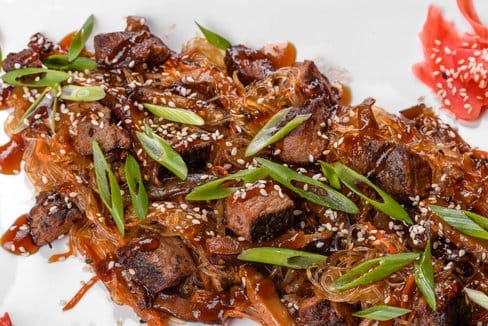 A plate of beef chow fun from Peter Chang, showcasing tender beef, wide rice noodles, and vibrant vegetables