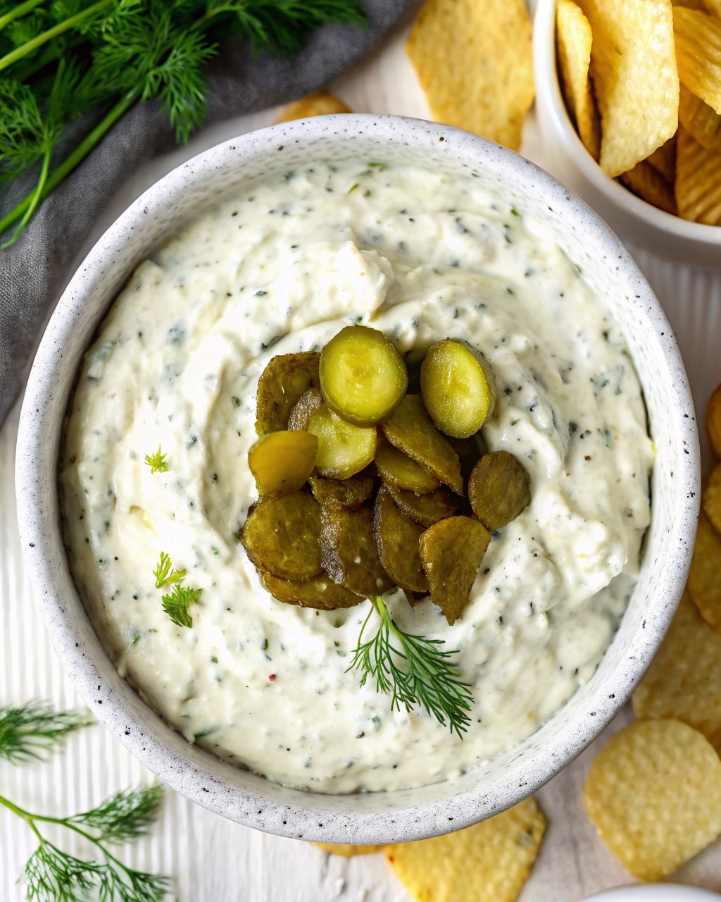 Dill pickle dip with cottage cheese served in a bowl with fresh dill